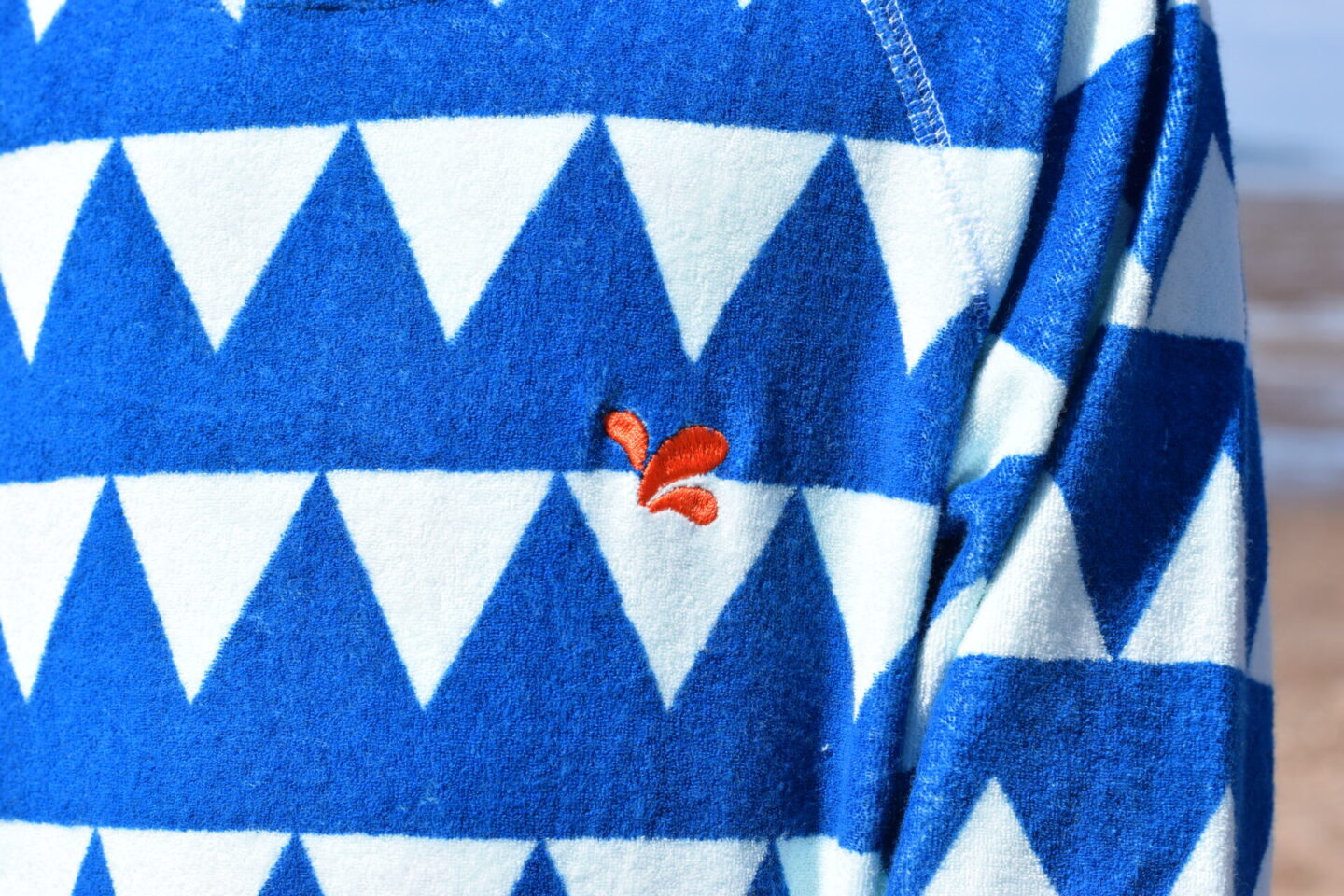 Muddy Puddles logo on the blue triangles towelling poncho