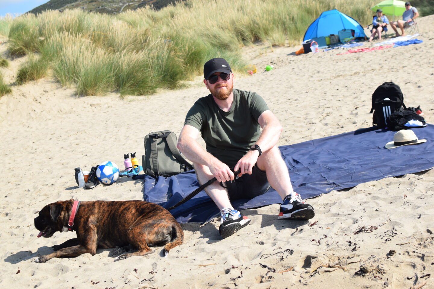 Dave and Poppy sitting on the navy XXL picnic mat on the beach