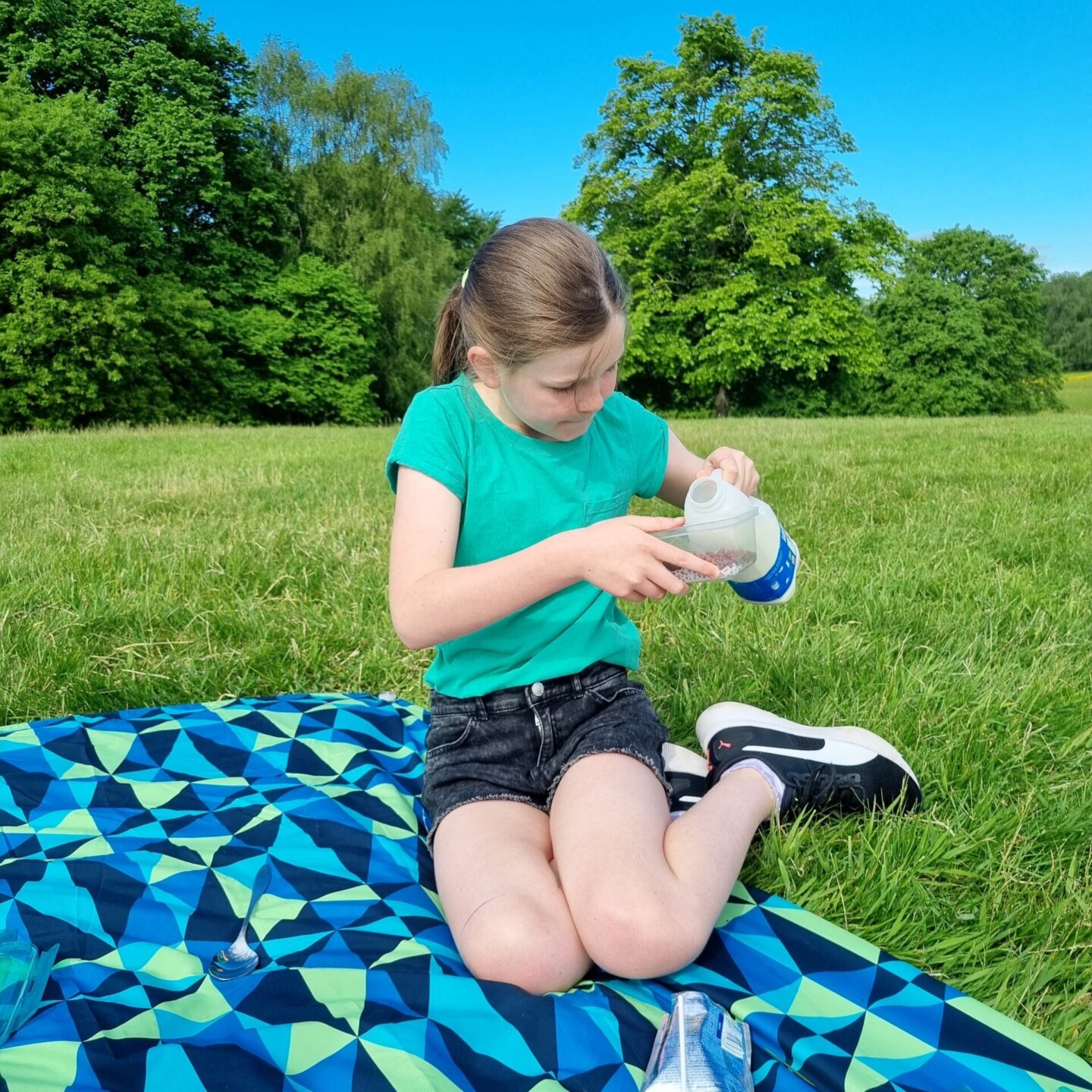 Pouring milk into a tupperware box of cereal on a breakfast picnic