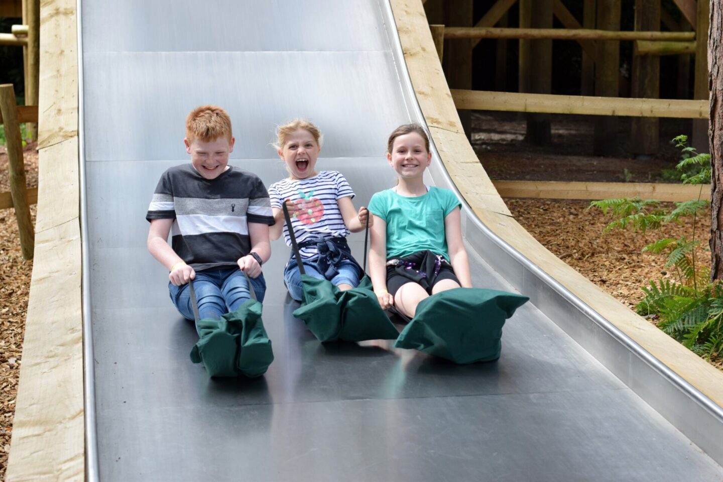 Siblings playing on the widest slide at BeWILDerwood