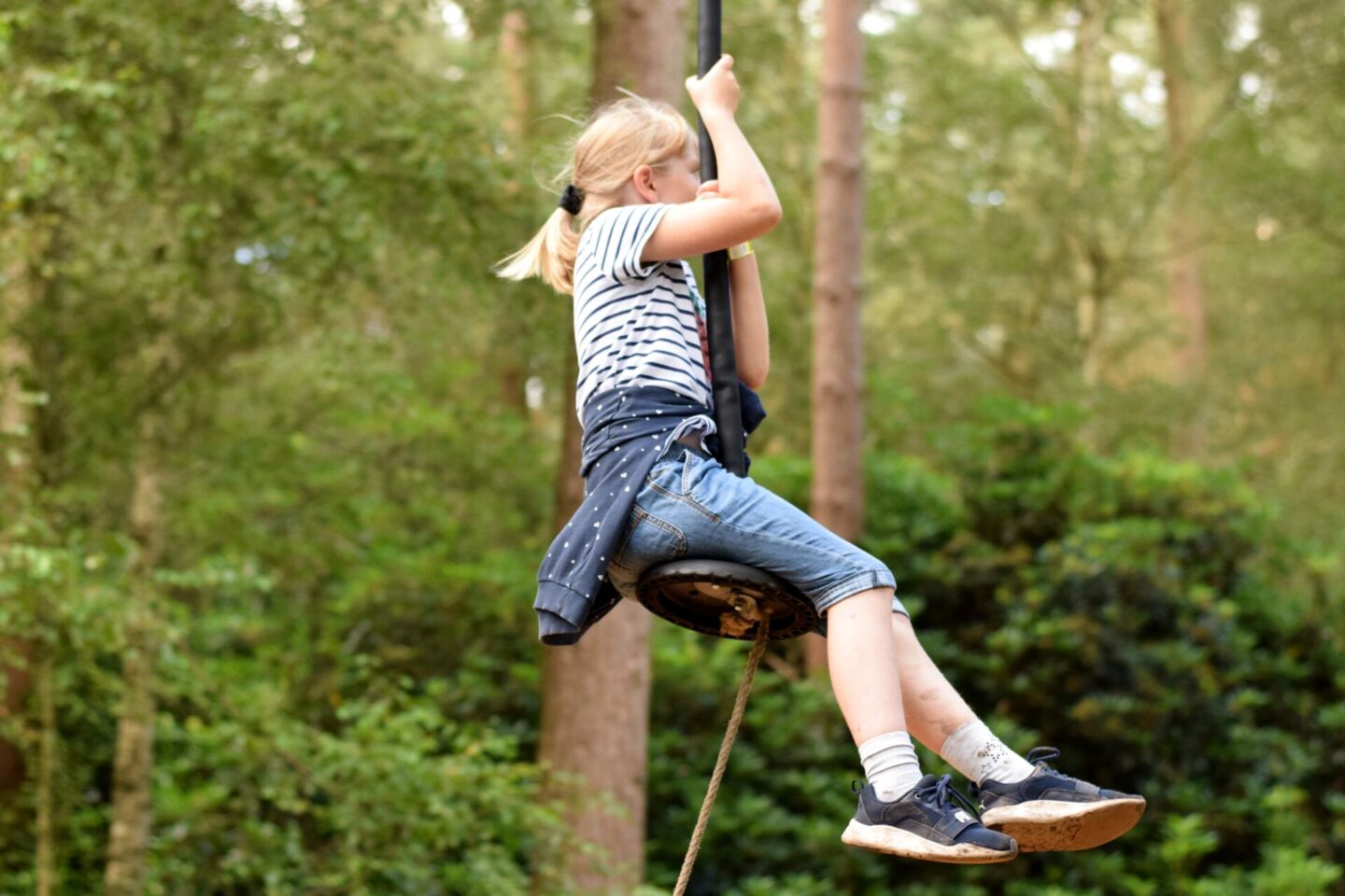 Little girl with muddy legs playing on the zipwires