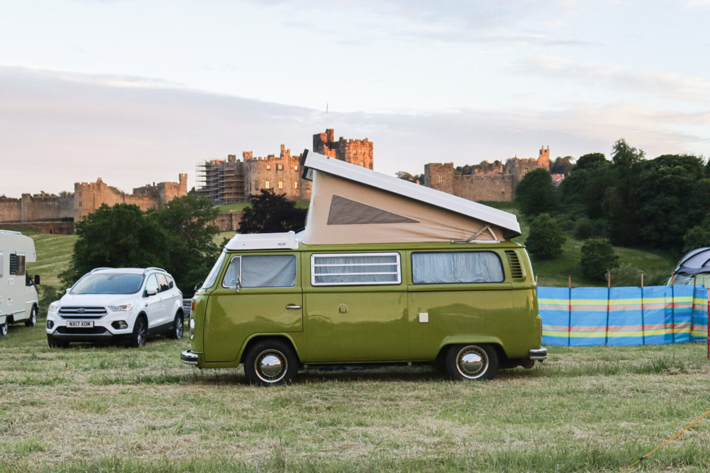 Green vintage camper van with Alnwick Castle in the background - parked up at Mighty Dub Fest - a uk vanlife festival