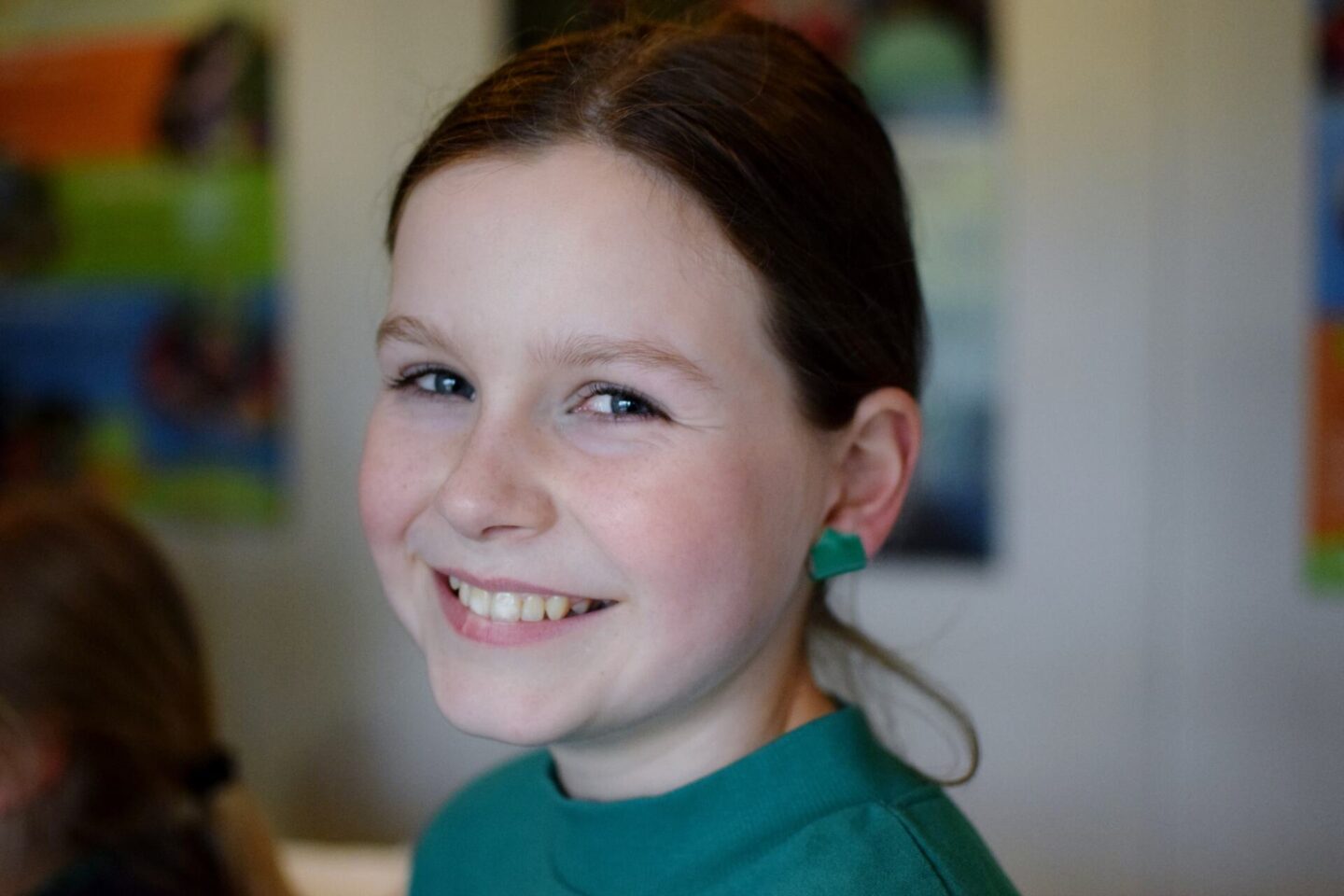 Chloe is smiling at the camera and has her earrings covered up with bright green tape ready for her TreeTop Trek experience