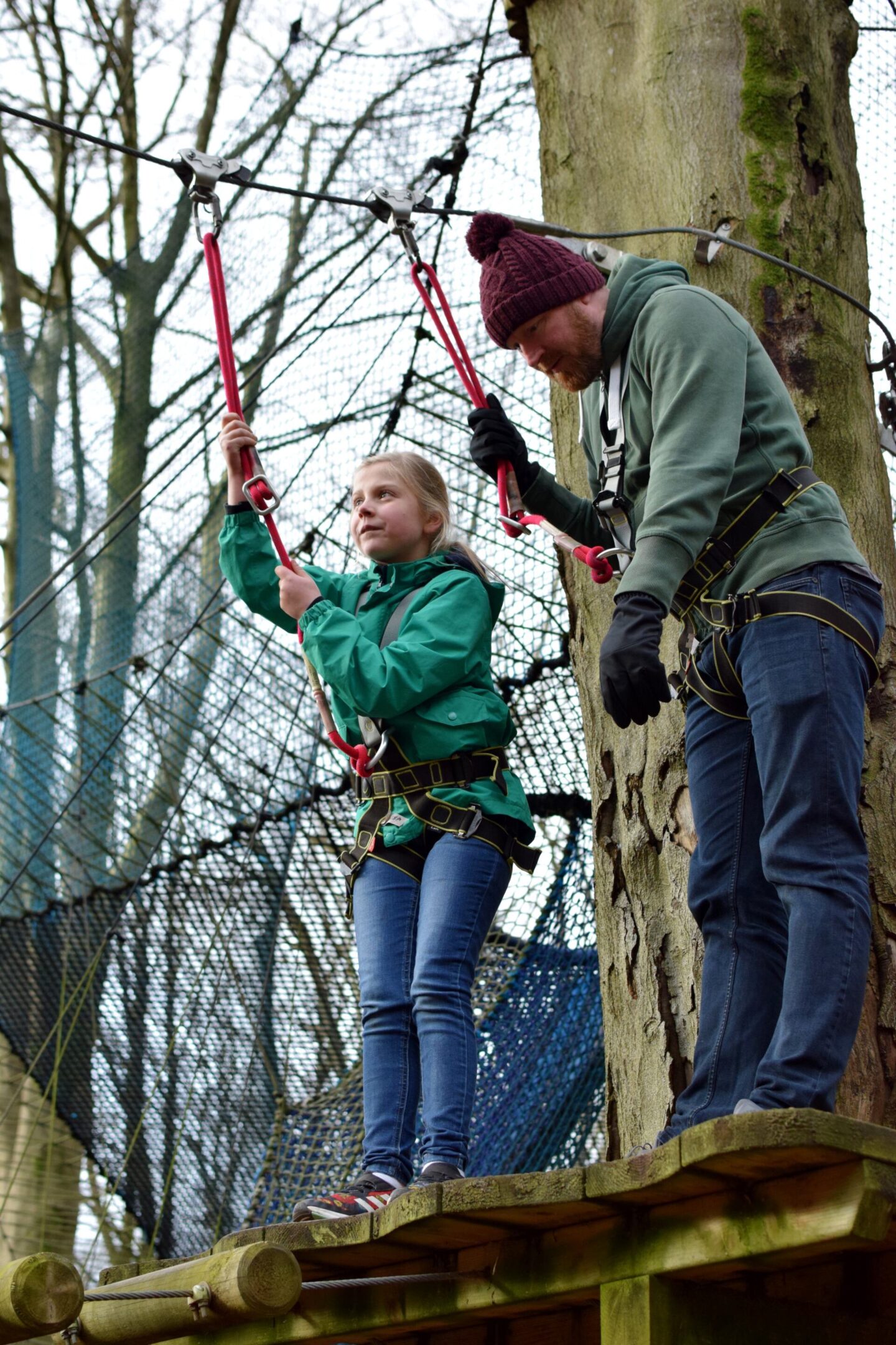Dave and Amy are standing on a platform waiting for Amy to be jump off on her first zipwire of the afternooon