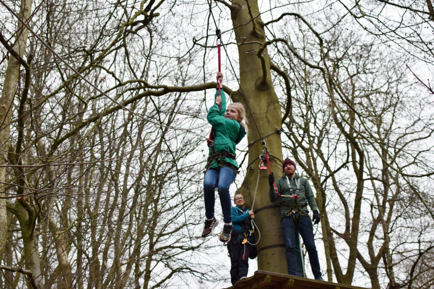 Amy is flying mid zipwire while her Dad and TreeTop Manchester staff look on. Amy looks relaxed and is enjoying herself