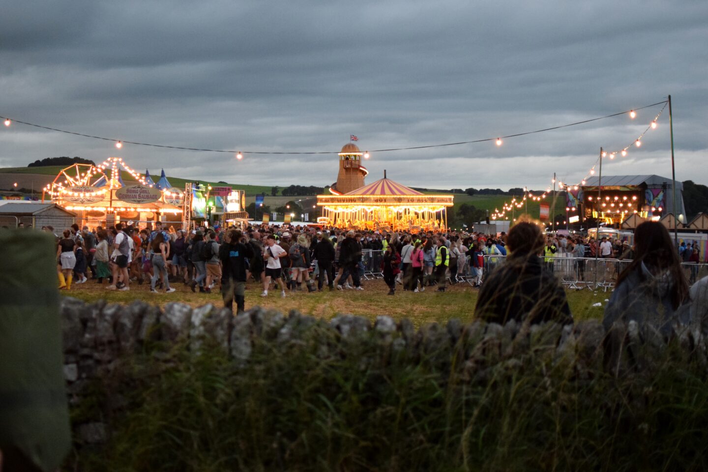 Y Not Festival 2023 at night - lit up fair ground rides and crowds leaving the festival arena