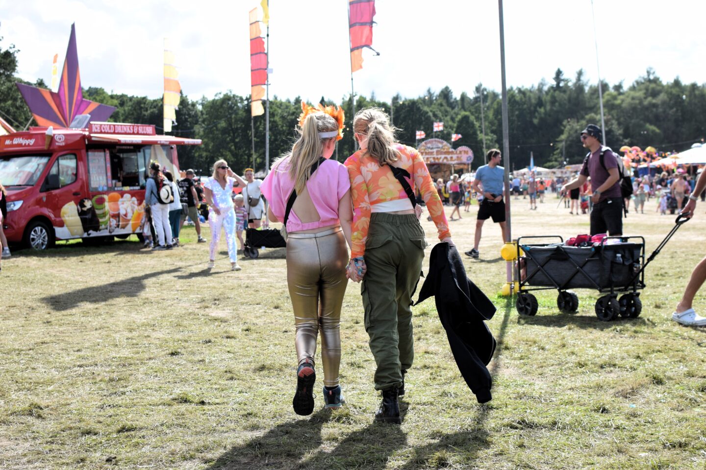 Amy and Ruby holding hands and chatting as they walk through the festival site.