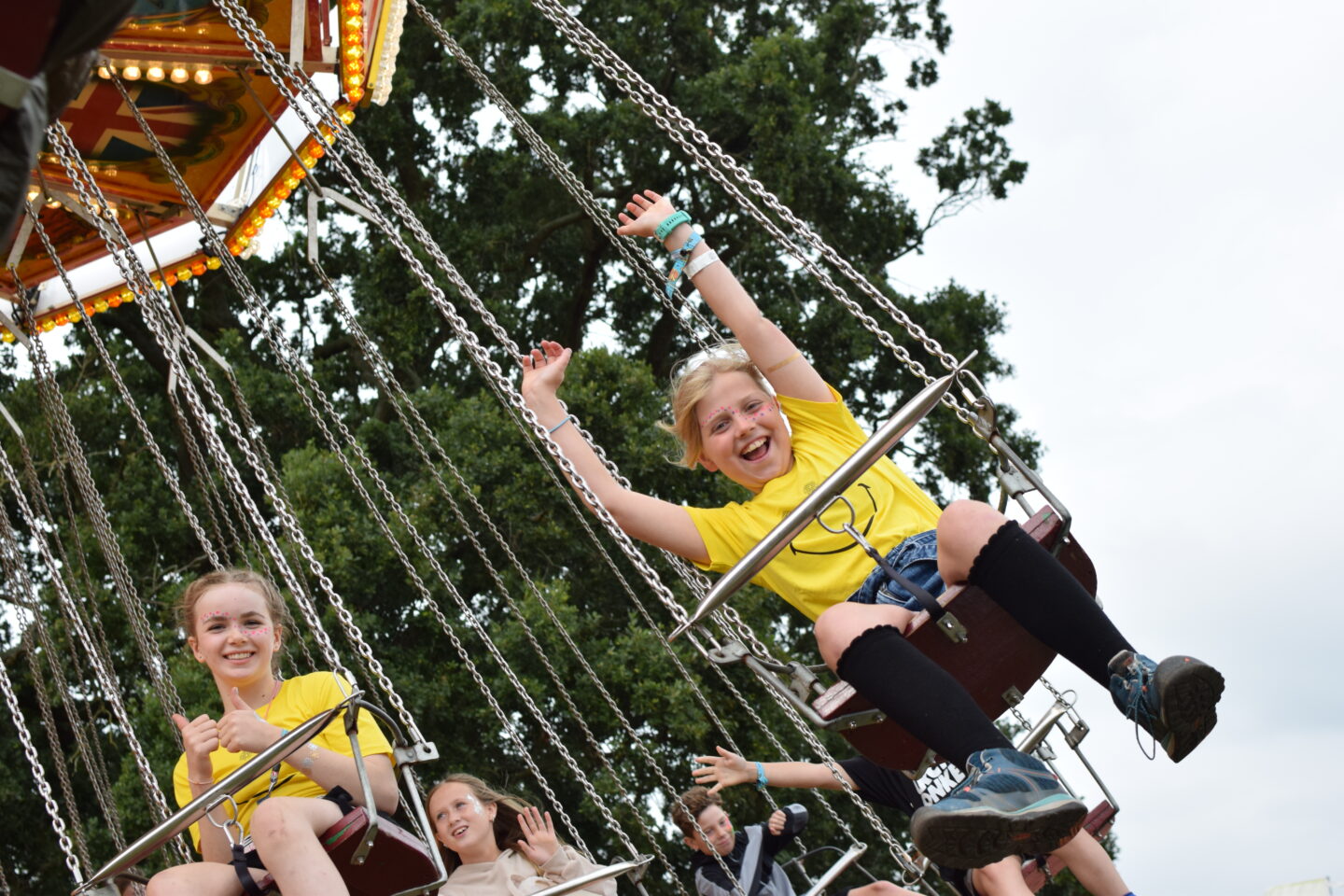 Amy on the swings at Camp Bestival with her arms in the air and a big grin on her face