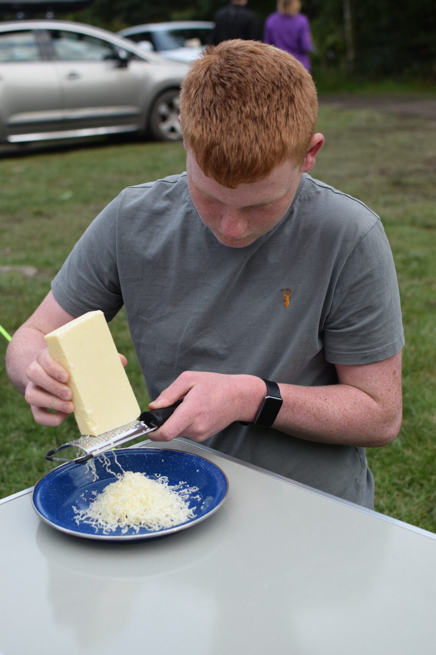 Camping chores for kids - Ben grating cheese for dinner