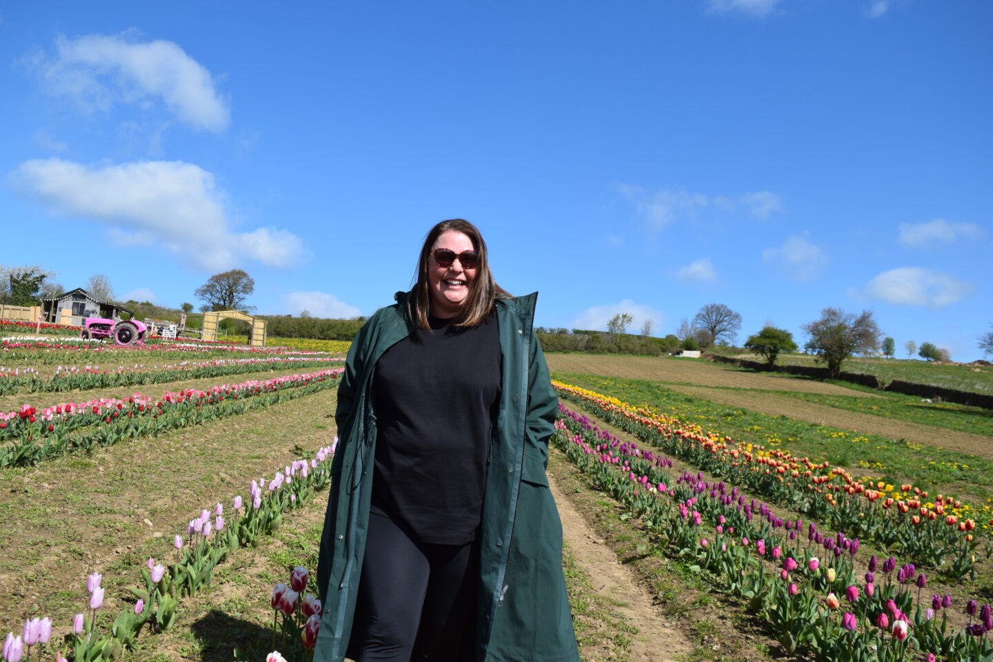 Colette beaming at the camera in a tulip field in North Yorkshire with bright blue skies