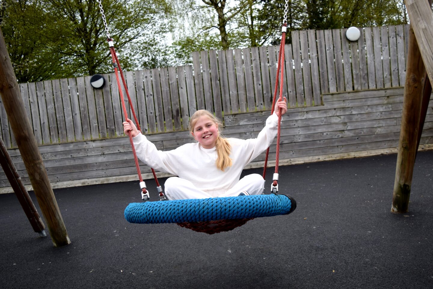 Amy sitting in the basket swing with her legs crossed smiling at the camera