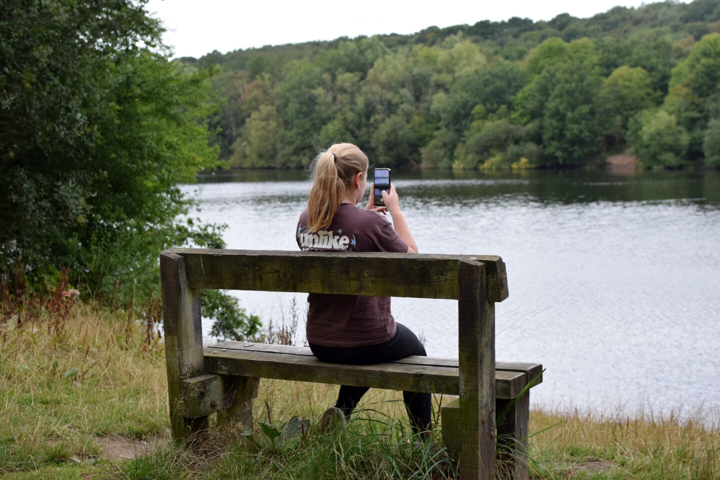 Amy sitting on a bench next to the lake in Clifton Country Park