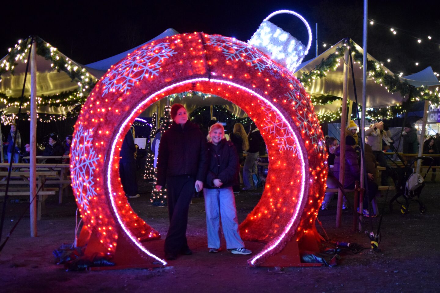 Chloe and Amy pose inside a giant red bauble at Northern Lights Manchester