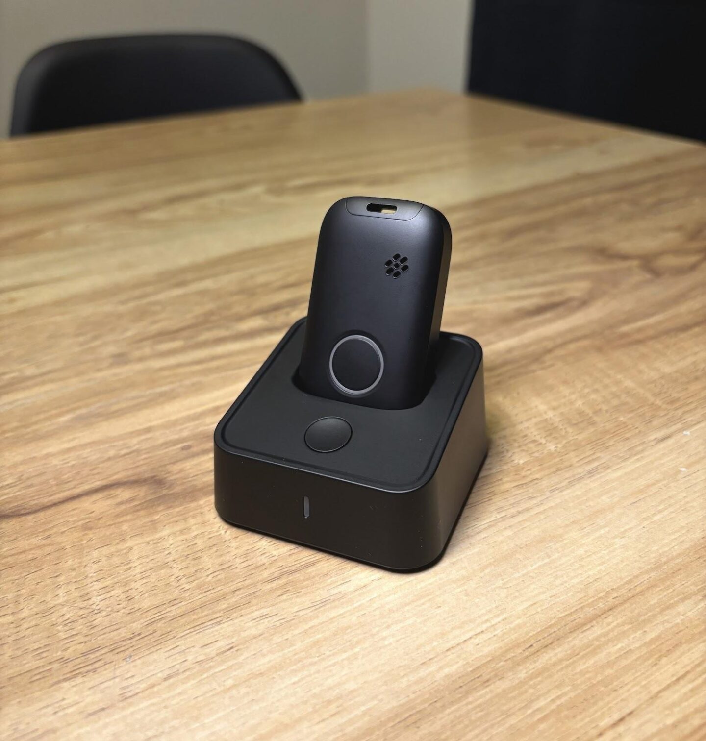 A medical alert device resting on its charging cradle at home